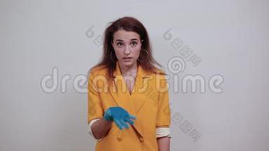 穿着黄色夹克的疲惫的年轻女子，戴着蓝色手套，双手放在头上