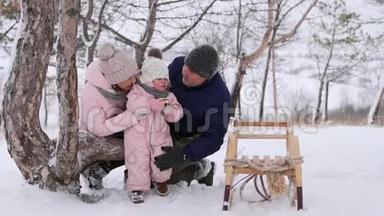 穿着粉红色<strong>冬季</strong>连衣裙的小女孩在<strong>雪天</strong>上雪橇后吃圣诞姜饼。 可爱的家庭过冬