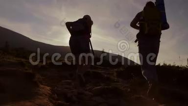 黎明时爬山。 两个游客在阳光下爬上山道