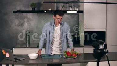 穿休闲服装的年轻人在灰色厨房里领导一个烹饪博客和录制视频。 博客的视频拍摄-