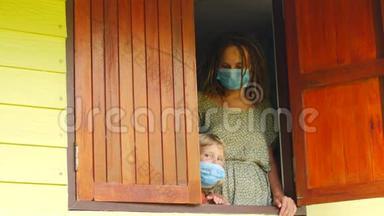 妈妈和女儿戴着防护面具在窗户里。 <strong>传染病</strong>，检疫，病毒。 COVID-19