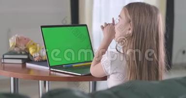 可爱的白人女孩坐在chromakey笔记本电脑屏幕前<strong>聊天</strong>。<strong>学生</strong>在线学习或使用社交