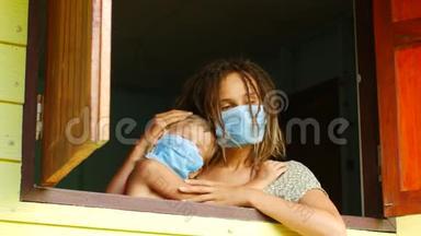 妈妈和女儿戴着防护面具在窗户里。 传染病，检疫，病毒。 COVID-19