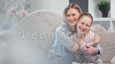 可爱的微笑的年轻妈妈拥抱着可爱的女儿，在灯光的包围下摆着姿势