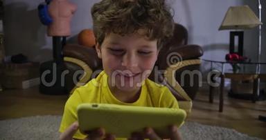 专心的白人男孩在智能手机屏幕上看一些有趣的东西。快乐的孩子看着屏幕笑