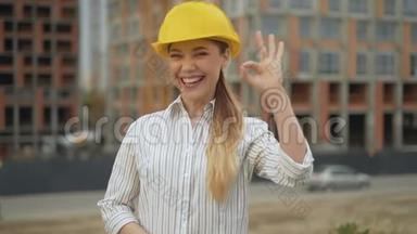 好的！ 自信、快乐、戴着安全帽的女建筑师看着摄像机，<strong>露出</strong>了一个好的姿势
