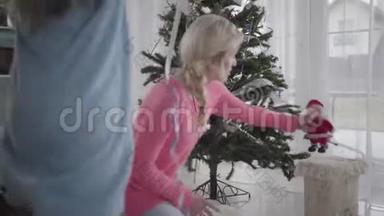 <strong>小白</strong>种人女孩帮妈妈装饰圣诞树的背面。 美丽的金发<strong>白</strong>种人女人和她