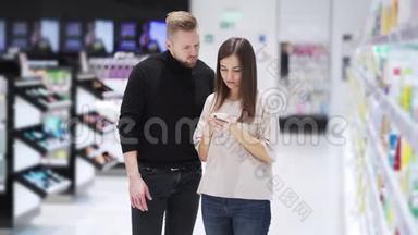 <strong>化妆</strong>品店里的丈夫和妻子看着智能<strong>手机</strong>聊天