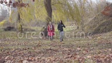 快乐的中东男友和白种人女友漫步在秋天的森林中的树木之间。 免费嬉皮士