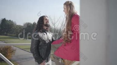 留胡子的中东男人的肖像，留着<strong>长长</strong>的卷发，和他漂亮的高加索女朋友交谈。 穿粉色衣服的女人