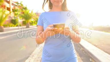 日落时分，一个穿着智能手机<strong>的</strong>蓝色裙子<strong>的</strong>女人在棕榈街散步