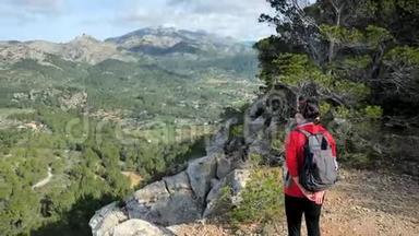 探索旅行目的地概念。 徒步旅行女人与背包在岩石的观点，在马洛卡岛山脉。