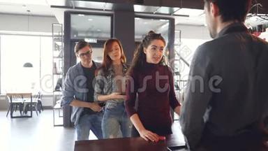 一个健谈的年轻女子正在咖啡馆的柜台和收银员聊天，而不耐烦的人们则排着长队