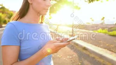 穿着蓝色连衣裙的女人，用智能手机，站在热带风景的街道上