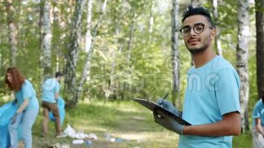 英俊的阿拉伯学生环保活动主义者在清理期间持有森林文件