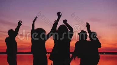 欢乐的<strong>学生</strong>在日落时在海滩上跳舞，<strong>一起</strong>在户外聚会上放松