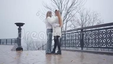 年轻的复<strong>古风</strong>格白种人夫妇在灰色天空的背景下在桥上跳<strong>舞</strong>。 穿着时髦白衬衫的年轻人