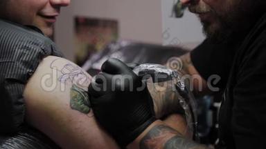 专业纹身师在男人手臂上做纹身。