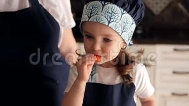 一个戴着帽子和围裙的可爱小女孩在厨房里吃番茄