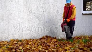 秋天工人在家附近吹树叶.