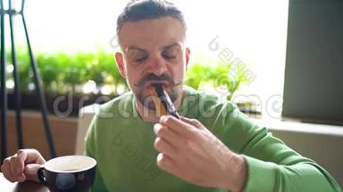 留着卷曲胡子的大胡子男人在咖啡馆里吃巧克力，喝咖啡