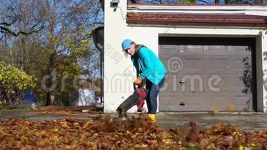 今年秋天，一位被雇佣的女工在车库门口吹树叶