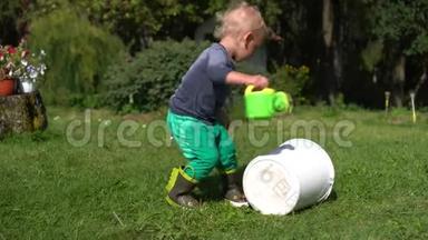 快乐的学步男孩在外面玩水缸和水桶