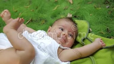 小女孩躺在公园草地上的地毯上。 梦幻般的新生婴儿躺在户外草地上。