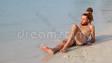 一个人在平静的大海附近的海滩上打太阳，一个人享受阳光和孤独