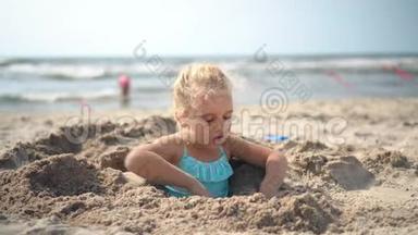 五岁的女孩被埋在沙子里<strong>挣脱</strong>逃跑了。 模糊的人和海洋