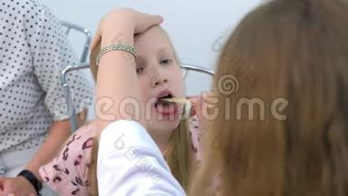 童女在<strong>儿科医生</strong>张口，医生用铲子看喉咙。