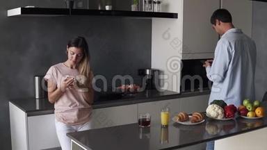 年轻夫妇在厨房的智能手机屏幕上看着一些现代阁楼设计的东西。 晨读