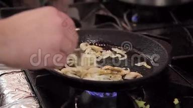 厨师在一个铸铁煎锅里把蘑菇和洋葱调羹。