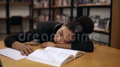 一个穿黑色毛衣的美国黑人女学生，累了，在一张桌子上睡着了，桌子上有现代的书籍和笔记