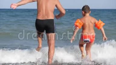 海滩<strong>暑假</strong>。 一个男人和一个<strong>孩子</strong>跑进汹涌的大海里潜水。