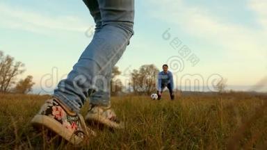 女孩`腿打足球男人<strong>接球</strong>。 一家人在公园里踢足球。 爸爸和女儿在球场上打球。