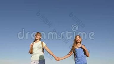 女孩们，女游客牵着手走在蓝天的背景上。 特写镜头。 团队合作游客青少年。 妇女