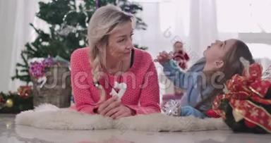 开朗的白种人黑发女孩在家和妈妈一起吃圣诞饼干时做鬼脸。 幸福的家庭开支