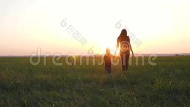 一位年轻的母亲牵着<strong>女儿</strong>`手。 幸福的<strong>一家人</strong>在夕阳下的清新空气中散步。
