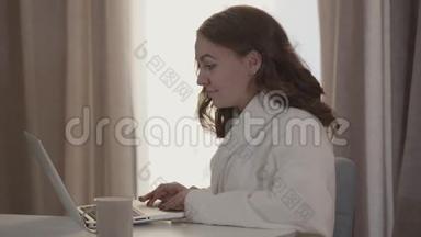 早上用笔记本电脑给白人女孩做特写。 年轻的美女，穿着<strong>白色浴袍</strong>，在社交场合