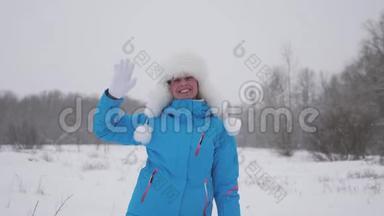 快乐的女孩在一个滑雪胜地挥手微笑。 圣诞节假期。 漂亮的女模特儿热情洋溢