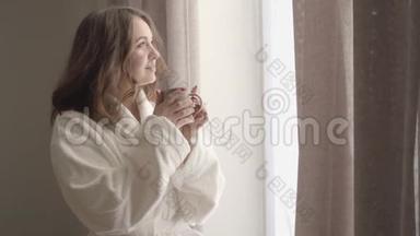 镜头慢慢接近年轻的黑发女人喝咖啡，看着窗外。 美丽的白人女孩