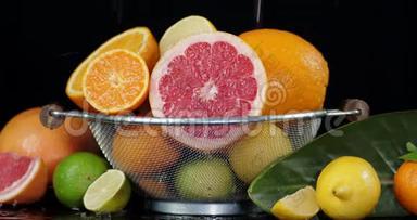 各种柑橘类水果在一个大山菜中，叶子落下水滴。