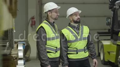 两个白人男子站在仓库和谈话的侧写。 在<strong>生产现场</strong>工作的员工.. 工厂