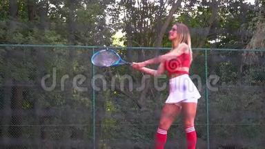 年轻漂亮的女人打网球。 一个穿红色<strong>运动服</strong>的<strong>女孩</strong>在训练网球