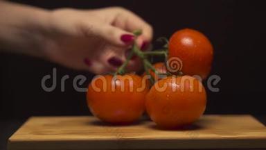 在现代化的厨房里，女人手的特写把一枝西红柿<strong>放在木板上</strong>。