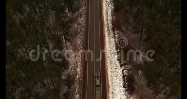 俯视空中。 乡间小路上的交通拖车和汽车在树林间的道路上。