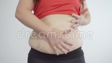 胖女孩胖乎乎的手放在他的肚子上。 纤维素和肥胖