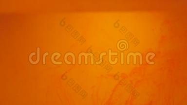 橙色粒子在橙色背景上上升。 墨水颜料混合在水中，缓慢地向上移动。 抽象油墨背景