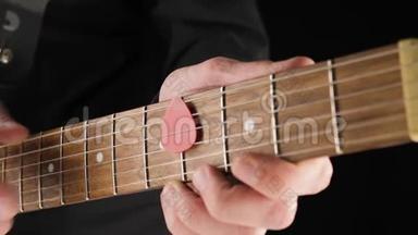 吉他手从浅棕色的六弦电吉他的琴弦拿一把红色的琴弦，背景是黑色的